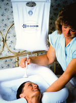 A woman uses a portable shower to wash another woman's hair in a basin sink