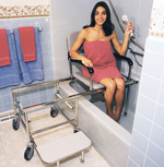 Woman in pink towel uses an RD Equipment handheld shower head while sitting in an RD Equipment sliding transfer shower chair in the bathtub