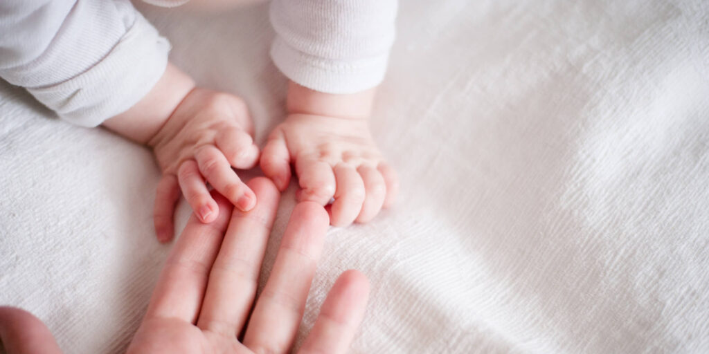 hands of a newborn baby in the mother's fingers on white background