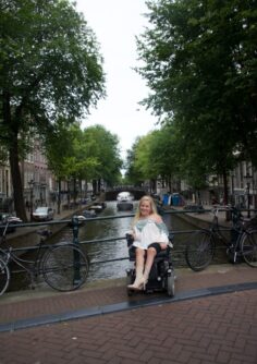 Jax Cowles in power wheelchair in front of a canal in Amsterdam