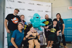 Six MDA and Magic Wheelchair team members gather around Carter in his wheelchair.