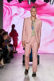 A man walks a fashion runway in a pink suit