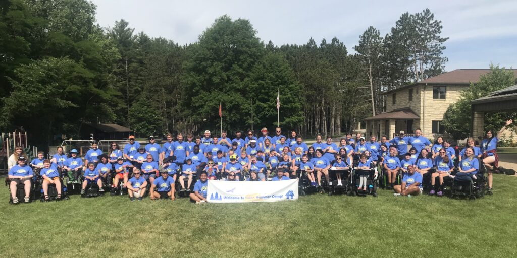 Campers and counselors pose together in front of pine trees