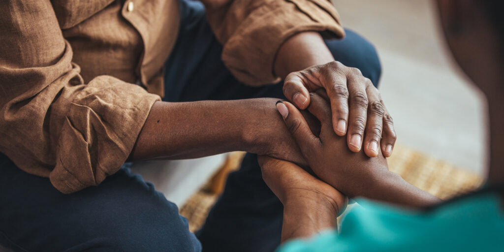 Close up of two people holding both hands in a supportive touch