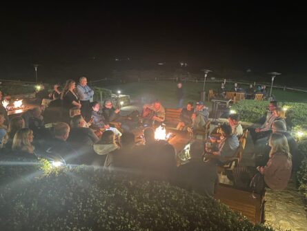 People gather around an outdoor fire in the evening
