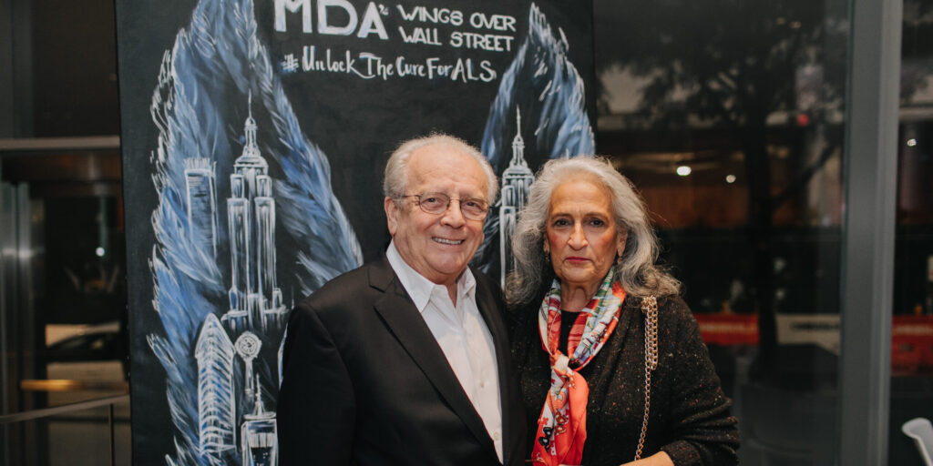 Victor Wright poses with his wife, Joann Wright, in front of MDA Wings Over Wallstreet angel wing sign