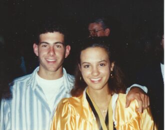 Teenage Jamie and Amy Shinneman smile, Amy wearing yellow graduation gown.