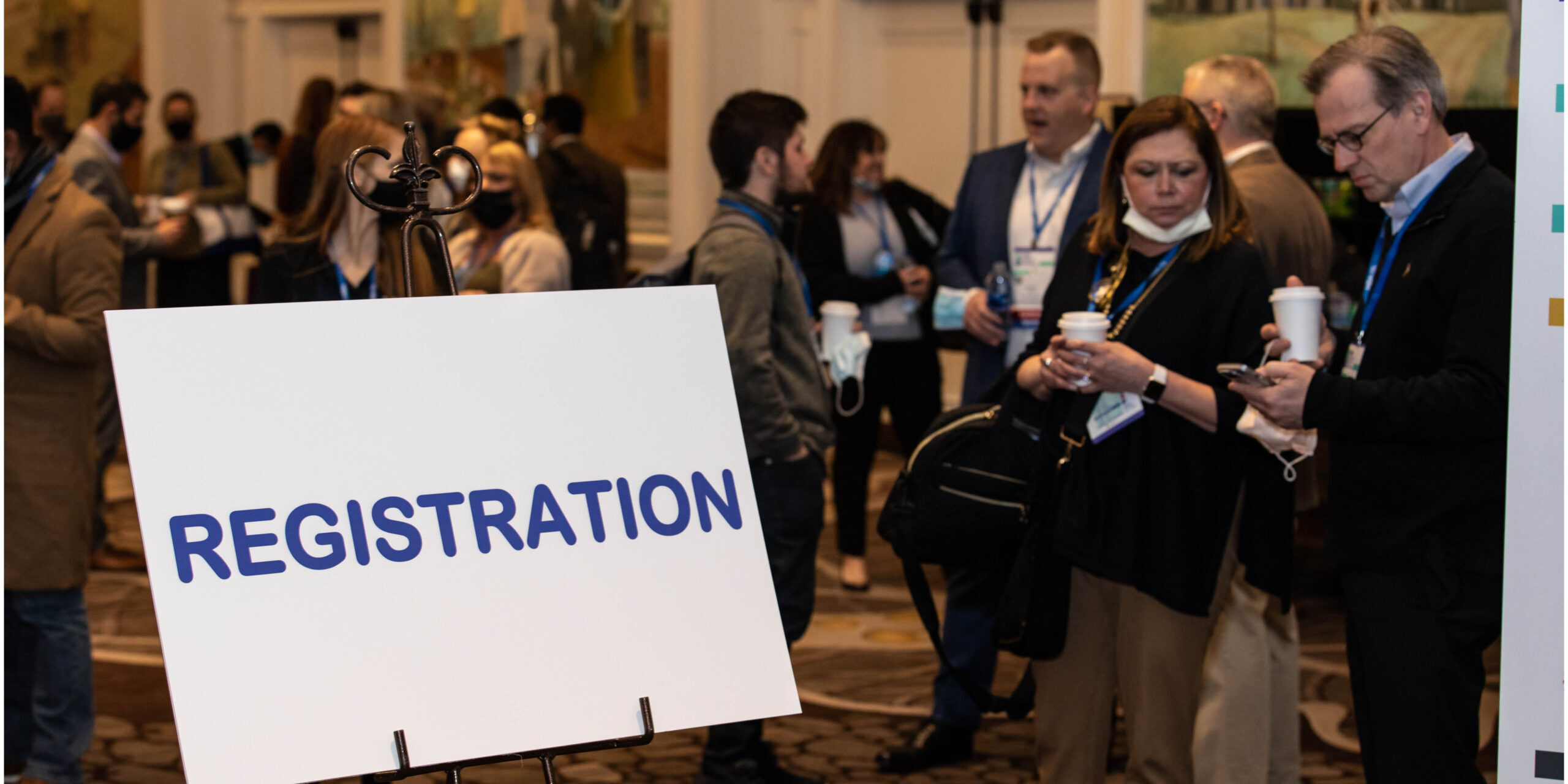 Registration sign for MDA conference in lobby room filled with people
