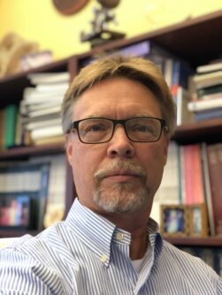 Closeup of Alan Beggs, PhD, a white man with short, straight blond hair, black-rimmed glasses, and a goatee.