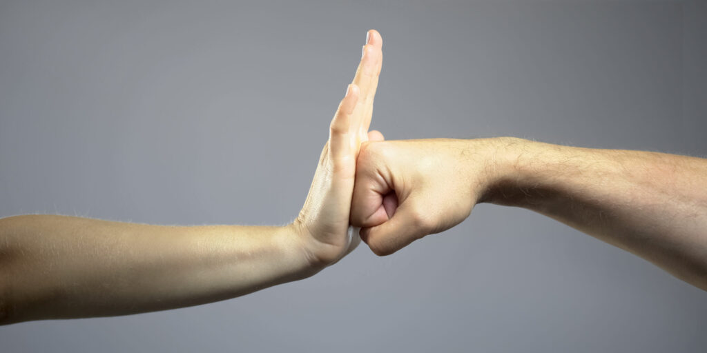 Side view of open hand pushing back against a closed fist