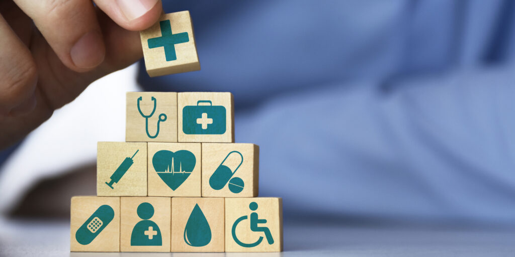 Men's hand arranging front view wood blocks with healthcare medicine icons