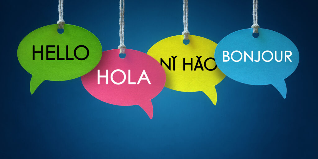 Foreign language colorful communication speech bubbles hanging from a cord over blue background