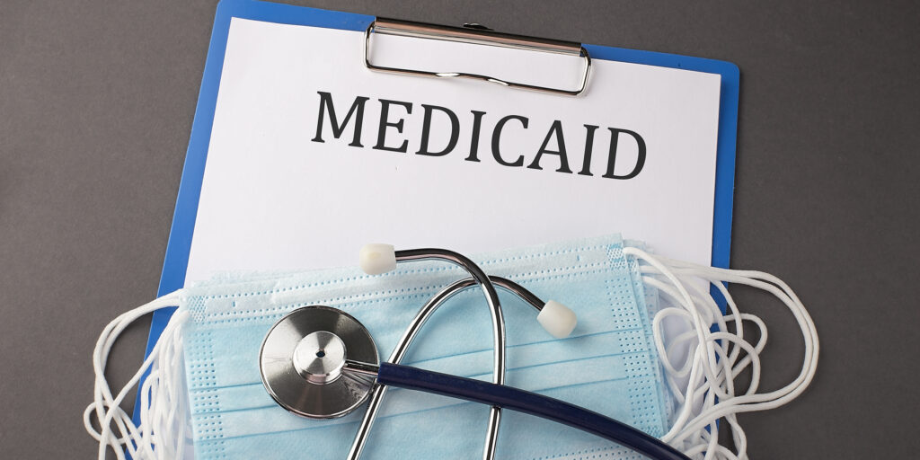 Folder with paper text MEDICAID , on a table with a stethoscope and medical masks