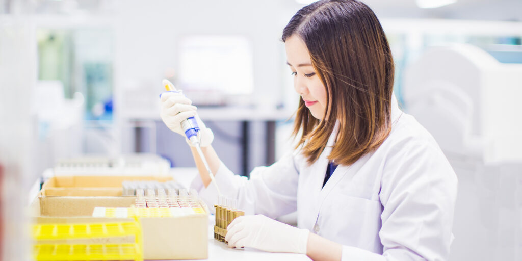 Researcher or medical technologist's pipetting samples into glass tubes.