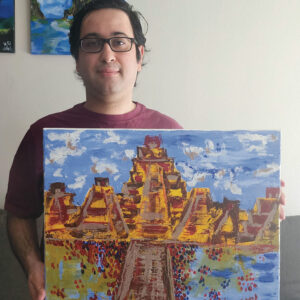 Closeup of Rodrigo Duran, a white man with black hair and black-rimmed glasses, holding a painting he made depicting Aztec pyramids.