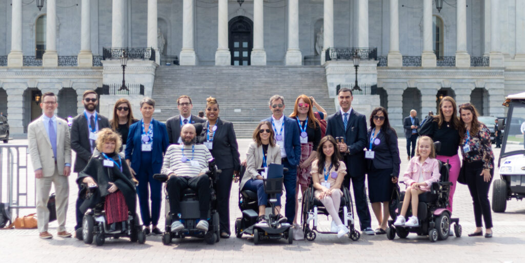 Advocates pose standing and sitting in wheelchairs in front of the Capitol in D.C.