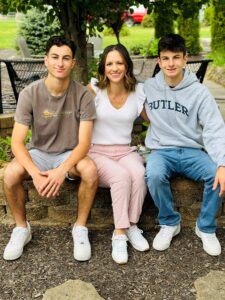 woman sitting o brick wall with her two teenaged sons 
