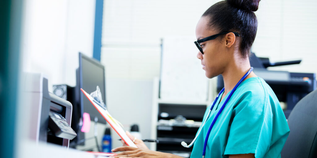 A female doctor or nurse concentrates while reviewing at a patient's test results.