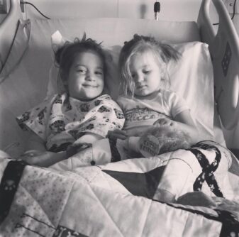 Black and white photo of two young girls in a hospital bed