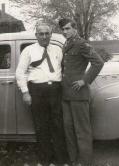 Black and white photo of two men standing in front of a car in the 1950s