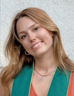 Headshot of a white woman with dark blonde hair and hoop earrings, smiling in front of a white backdrop