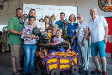 A young girl in a Magic Wheelchair costume is dressed as Rapunzel and poses with her extended family