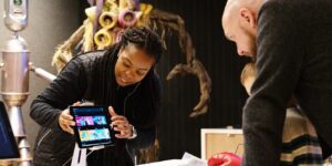 A woman shows a man and his child a screen in the Accessibility Lab