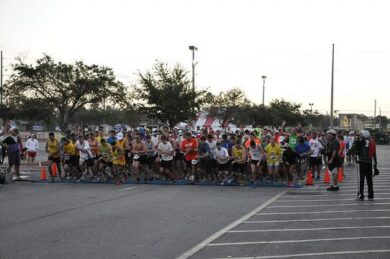 A large group of race participants gather in a parking lot