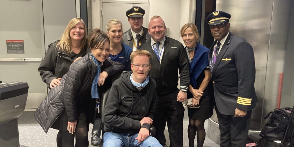 Don Talley sits in a wheelchair surrounded by flight crew