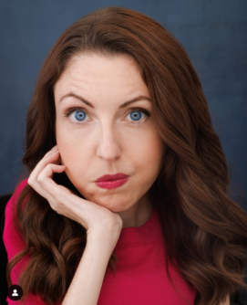 Shannon DeVideo headshot, woman with brown hair and blue eyes wearing a red shirt