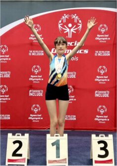A young woman stands on the first place podium in front at the Special Olympics