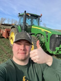 Jayston gives a thumbs up in front of a John Deere Tractor