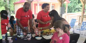Volunteers in Safeway t-shirts serve food at MDA Summer Camp