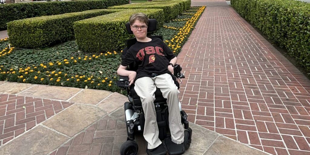 young man in wheelchair wearing a black USC shirt: August Johnson attending Explore USC.