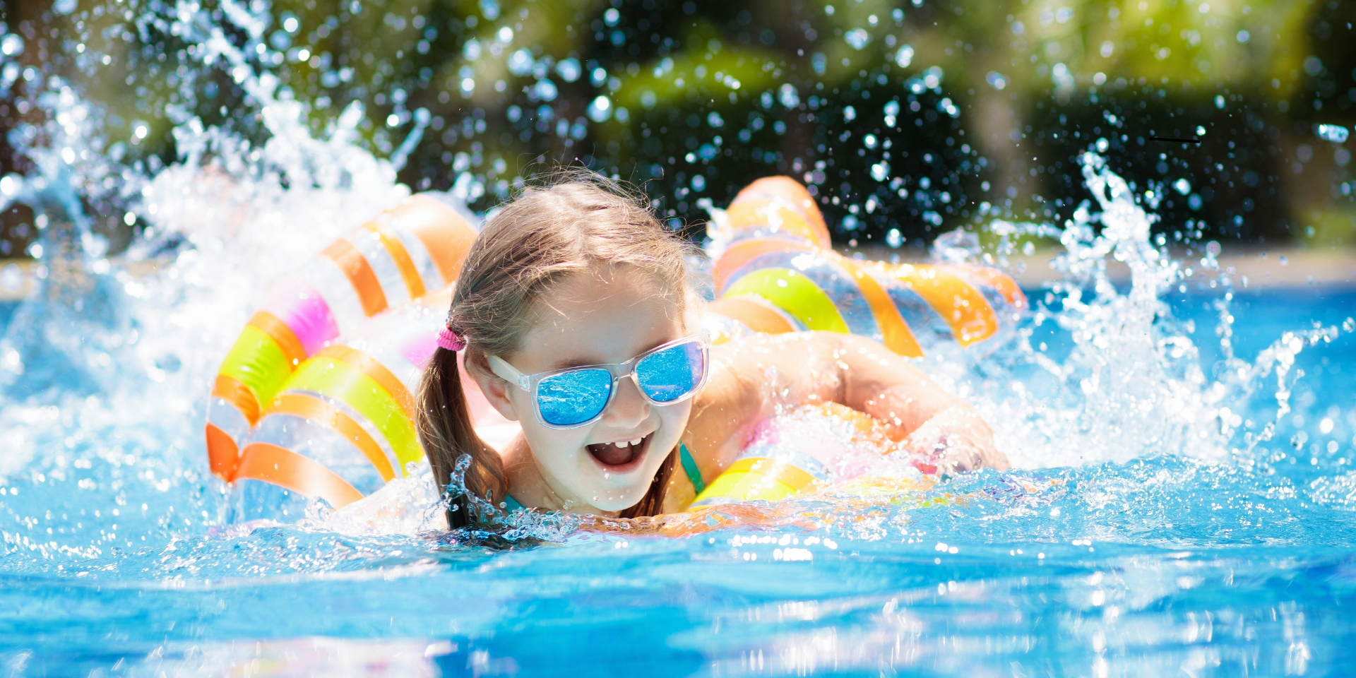 Child splashing in a pool with floatation devices and goggles