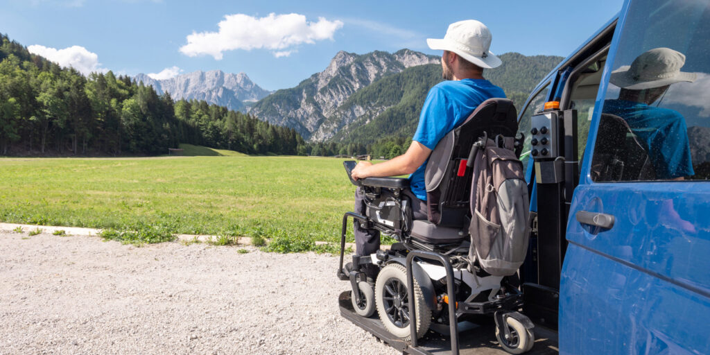 Man with disability a frequent traveller, getting off a van using the wheelchair lift after arriving in a mountain rest area