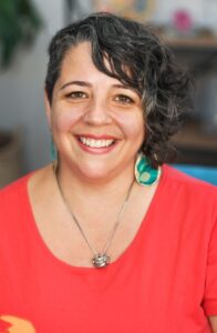 Headshot of Anna Goldberger, a woman with light skin and curly brown hair.