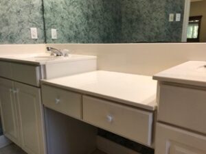 Bathroom counter with a lower vanity area between two sinks.