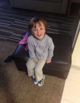 A small boy sits on a leather bench