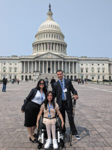 Teenager Leah, in a wheelchair, with her mother Bevi and father Jaime, standing with walking sticks, in front of the US Capitol building.