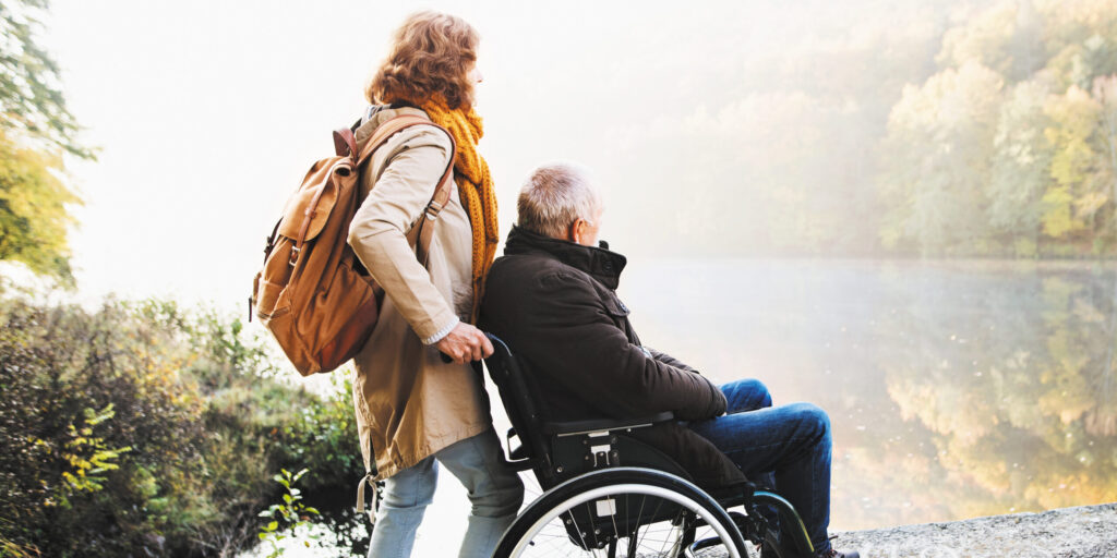 Two older adults enjoy the outdoors next to a picturesque lake.