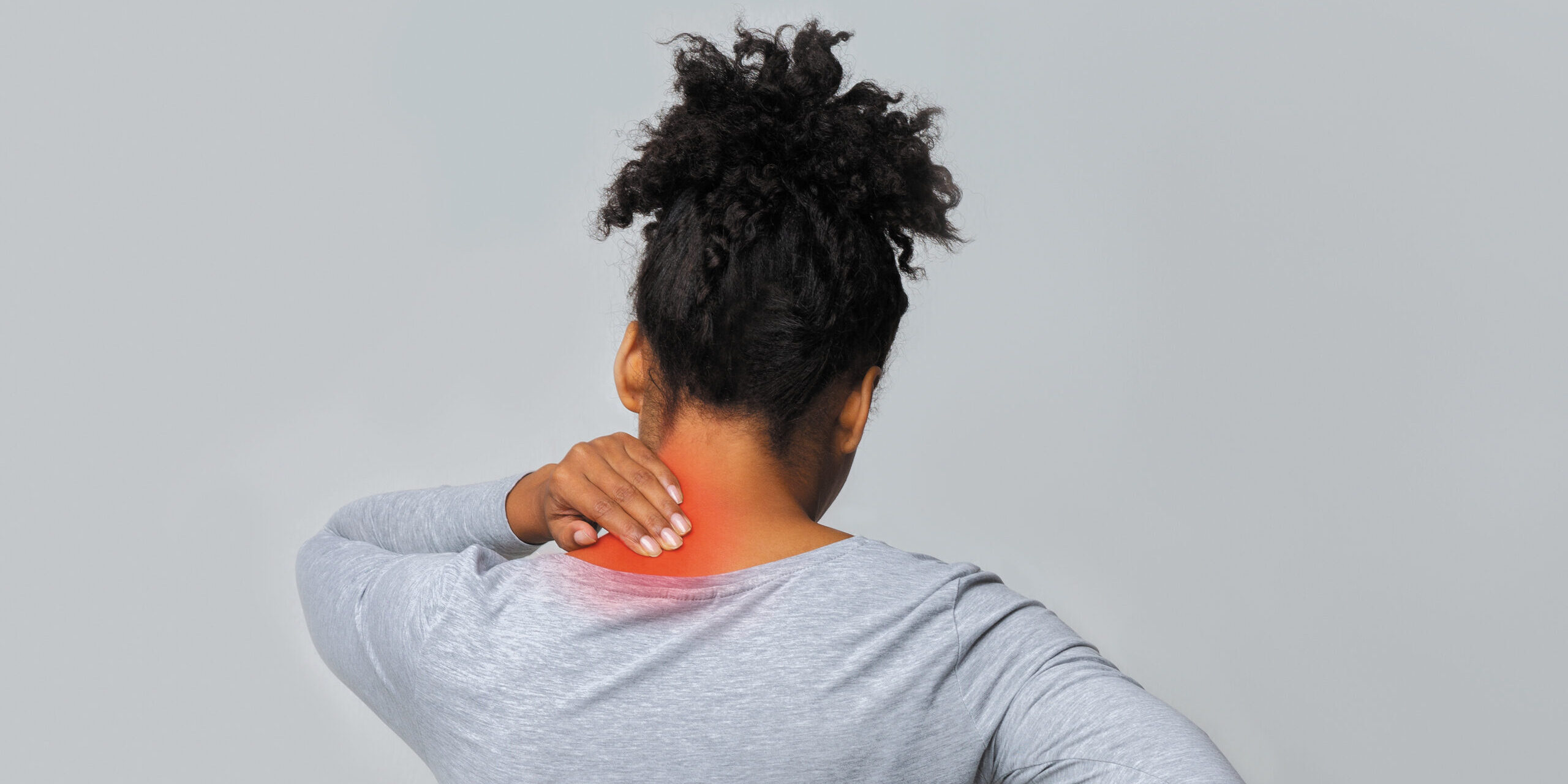 Back view of african woman rubbing her inflamed neck and loins, grey background