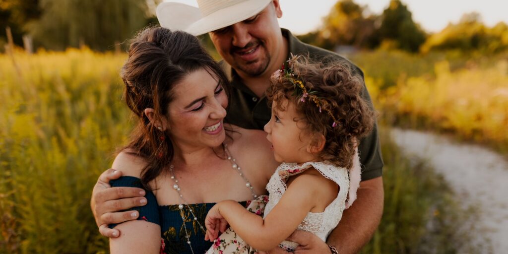 A mom and dad hold their daughter and smile at her