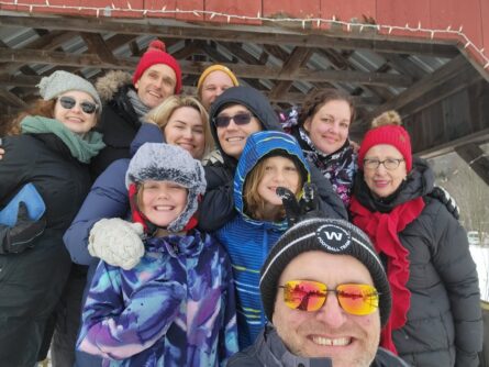 A large group pose for a selfie wearing snow hats and glasses