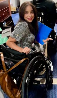 A woman in wheelchair holds a folder 