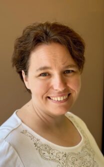 A photo of a woman with short brown hair smiling at the camera