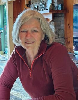 A woman with shoulder length blonde hair and a maroon sweater smiles at the camera