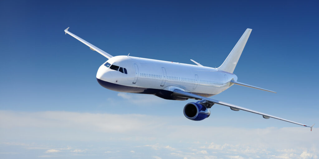 a white airplane flying in sky above the clouds