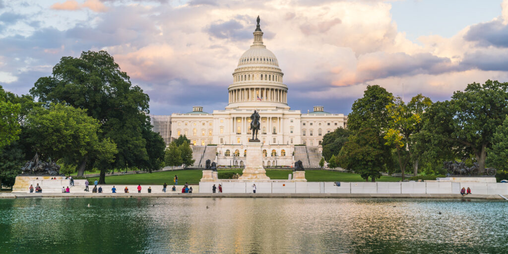 The United States Capitol building at sunset with reflection in water.