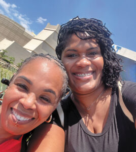 Selfie of Mashauna Black and another woman smiling at the camera with a clear blue sky behind them.